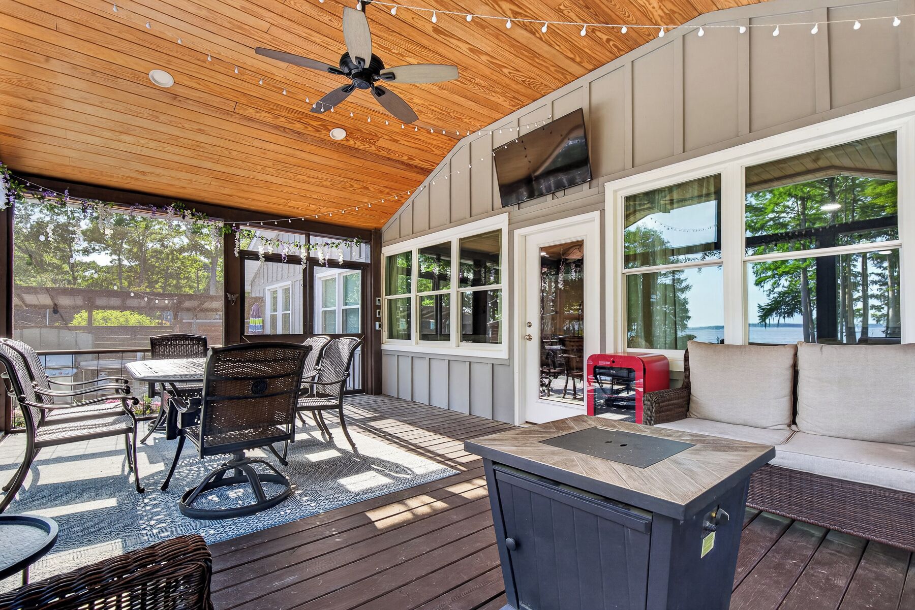 An outdoor patio with a ceiling fan, string lights, a grill, and seating.