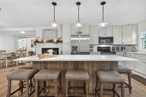 A modern kitchen with a large island, bar stools, stainless steel appliances, and pendant lighting. - Sandy Shores Pool & Spa Retreat w/Hot Tub/Beach (Summerton)