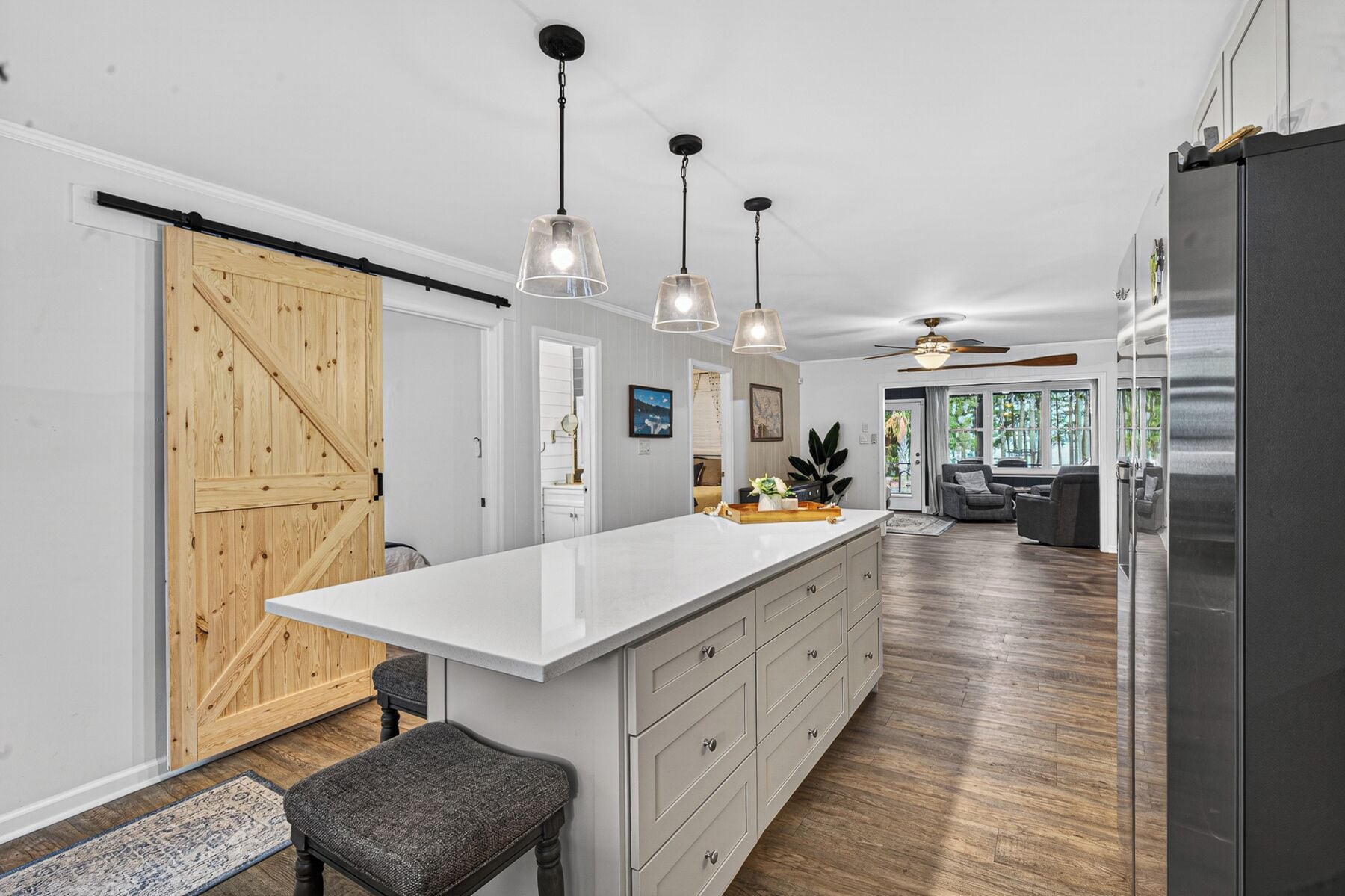A modern kitchen with a large island, pendant lights, and a sliding barn door.