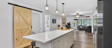 A modern kitchen with a large island, pendant lights, and a sliding barn door.