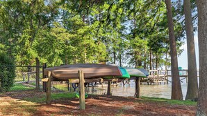 A covered boat storage area with a dock extending into a body of water, surrounded by trees. - Sandy Shores Pool & Spa Retreat w/Hot Tub/Beach (Summerton)