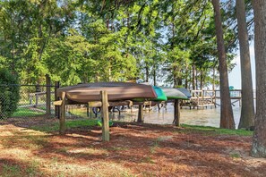 A covered boat storage area with a dock extending into a body of water, surrounded by trees. - Sandy Shores Pool & Spa Retreat w/Hot Tub/Beach (Summerton)