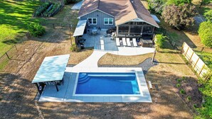 A residential property with a swimming pool, patio seating, and a covered outdoor area. - Sandy Shores Pool & Spa Retreat w/Hot Tub/Beach (Summerton)