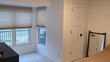 Un dormitorio con cama, cómoda, puerta y ventana con persianas.