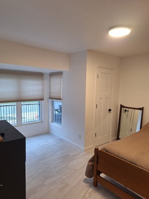 A bedroom with a bed, a dresser, a door, and a window with blinds. - 3-bedroom house in soothing Manistique with plenty of space to relax (Manistique)