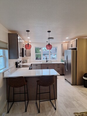 A modern kitchen with a large island, stainless steel appliances, and pendant lighting. - 3-bedroom house in soothing Manistique with plenty of space to relax (Manistique)