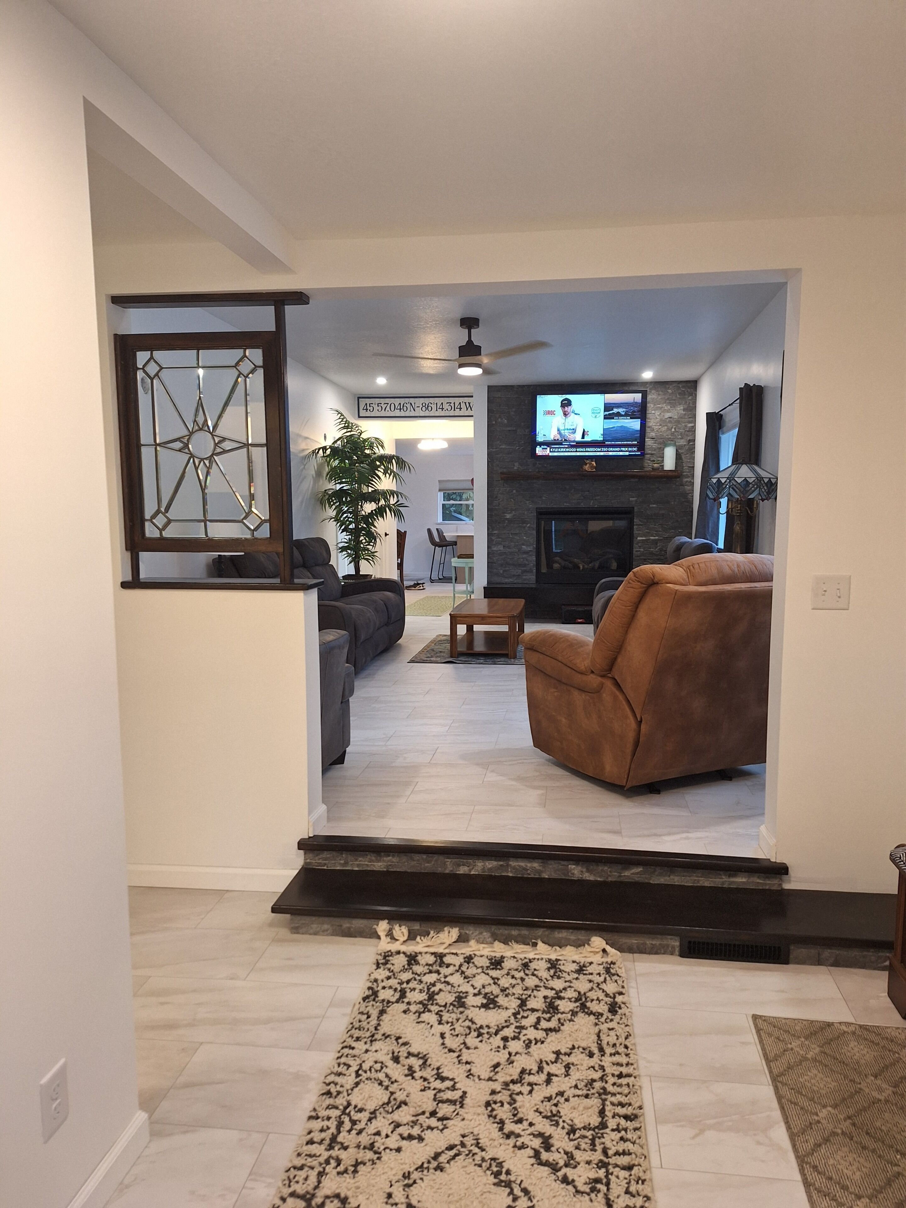 A modern living room with a fireplace, a television, and a seating area with a sofa and armchair.