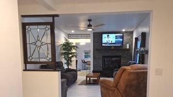 A modern living room with a fireplace, a television, and a seating area with a sofa and armchair.