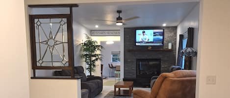 A modern living room with a fireplace, a television, and a seating area with a sofa and armchair.