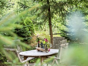 A round wooden table with chairs, surrounded by greenery and trees. - "Gesine" - 20km to the fjord by Interhome (Toftlund)