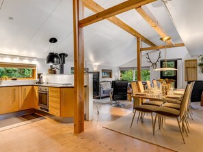 Cozinha estilo loft espaçosa com vigas de madeira, área de jantar com mesa alta e vista para o exterior.