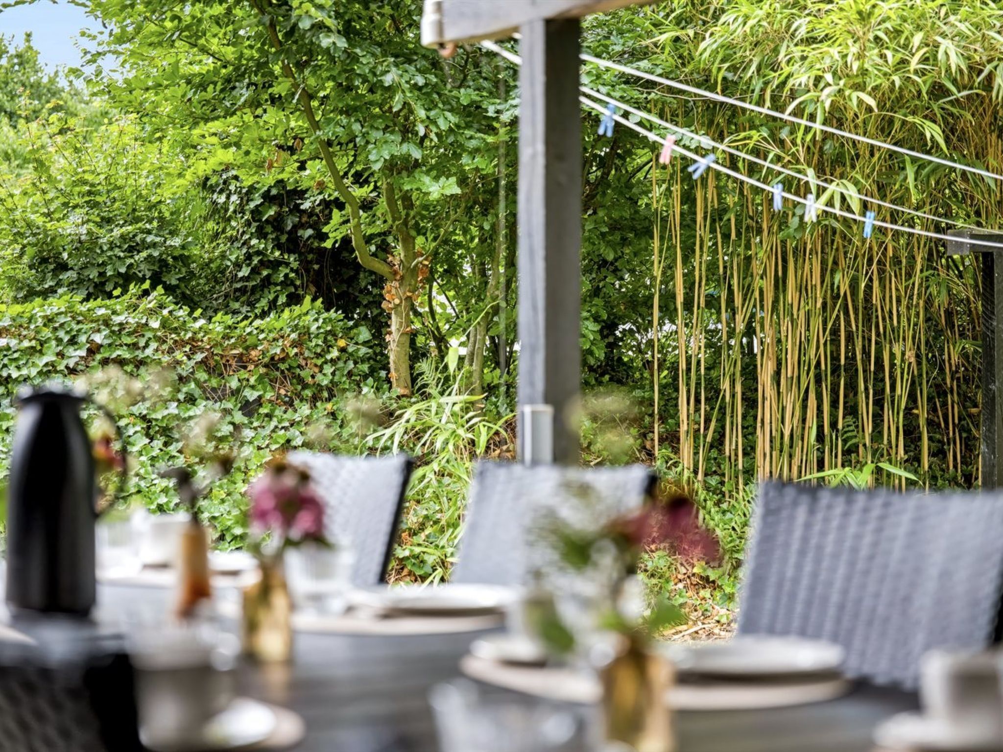 Un espace de restauration en plein air, avec des tables et des chaises, entouré d’une végétation luxuriante et agrémenté de décorations en bambou.
