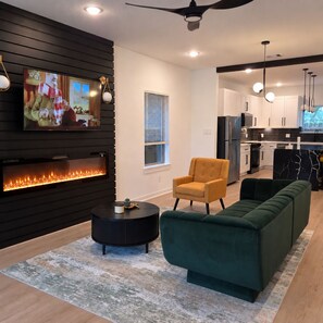 A modern living room with a fireplace, a sofa, a coffee table, and a television mounted on the wall. - Modern Retreat / Near Downtown• NRG • Med Ctr (Houston)