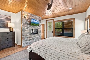 Ein Schlafzimmer mit einem Bett, einem Schminktisch, einem Fernseher und einer Steinwand.
