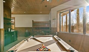 A pool table with billiard balls, a wooden bench, and a window with a view of trees. - Edgewood Retreat – Modern Luxury Cabin in Chalet Village (Gatlinburg)