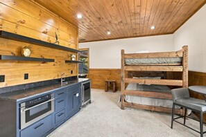 A compact kitchen with a built-in oven, a sink, and a small dining area with a bench. - Edgewood Retreat – Modern Luxury Cabin in Chalet Village (Gatlinburg)
