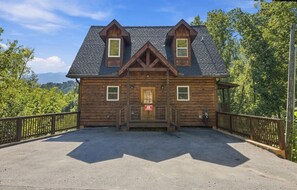 A wooden cabin with a steeply pitched roof, a front porch, and a fenced driveway. - Chestnut Tower – Incredible Mount LeConte Views, Hot Tub & Game Room (Gatlinburg)