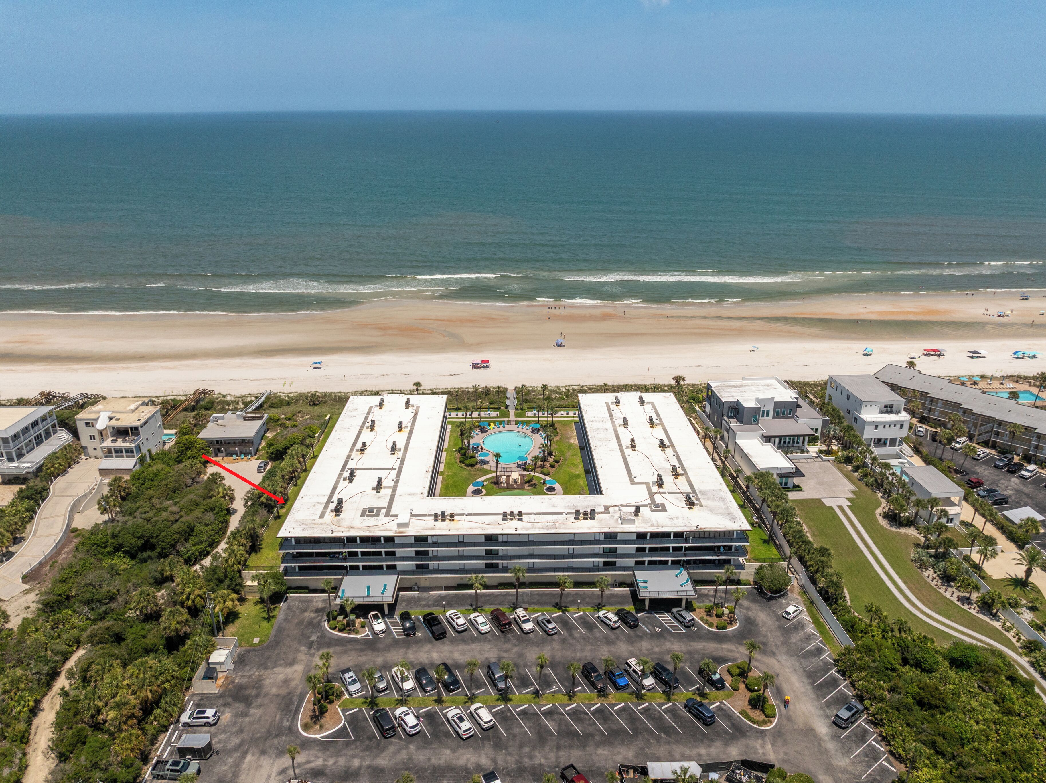 Ein Hotel mit Dachpool, Parkplatz und Blick auf den Strand.