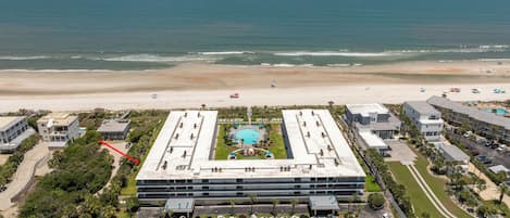 A hotel with a rooftop pool, parking lot, and beachfront view.