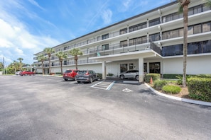 A multi-story parking structure with several cars parked, a handicap parking space, and a building with balconies. - Ocean House 317: 2BR, 2BA beachfront condo with pool, balcony, views (St. Augustine)