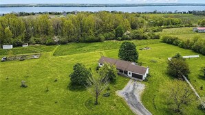 Uma propriedade rural com casa, campos abertos e um lago ao fundo.