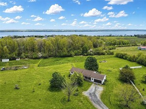Ein ländliches Anwesen mit einem Haus, offenen Feldern und einem See im Hintergrund.