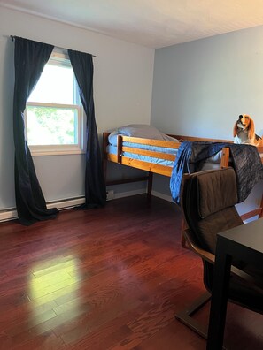 Ein Zimmer mit einem Etagenbett, einem Schreibtisch, einem Stuhl und einem Fenster mit Vorhängen.