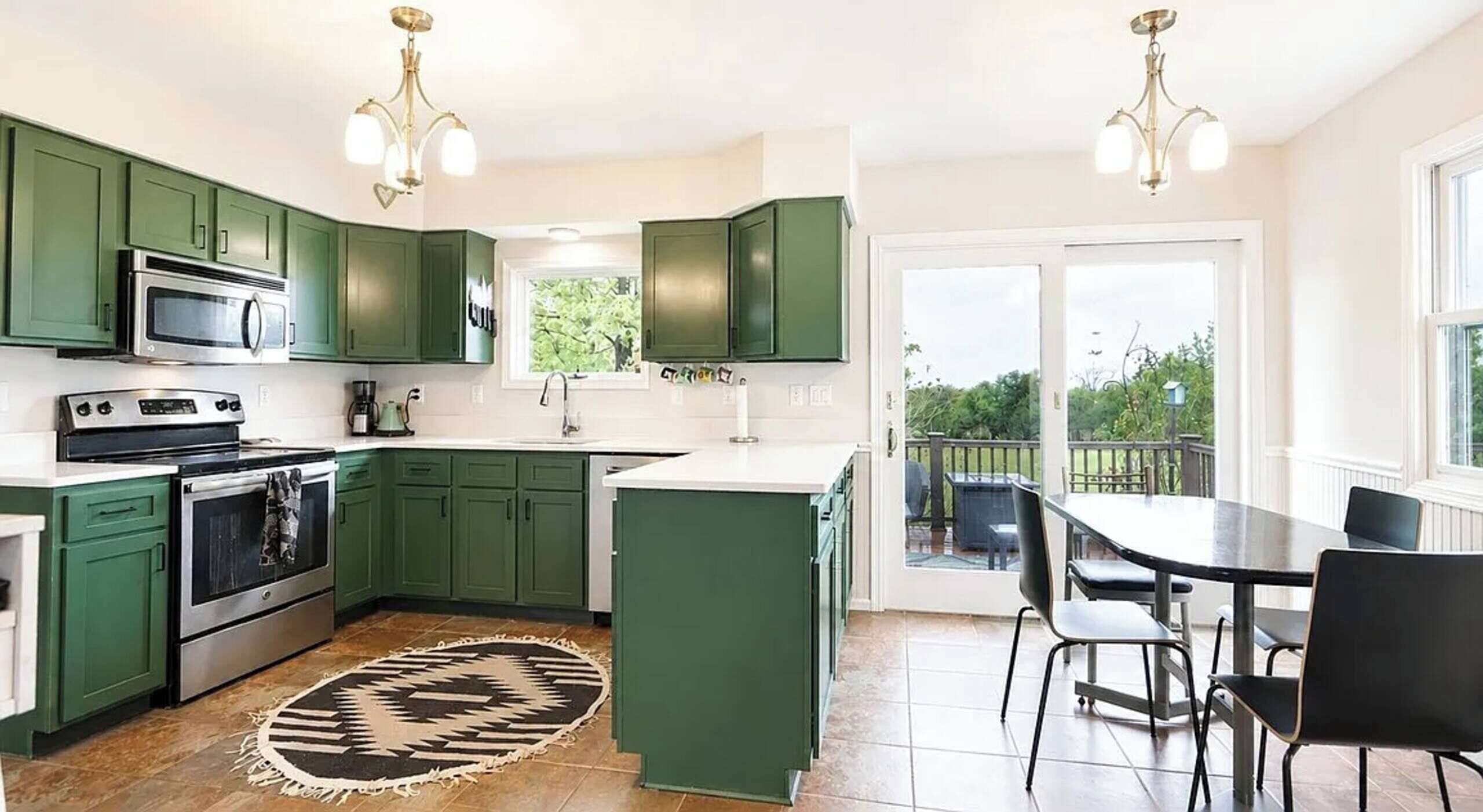 A modern kitchen with green cabinets, a central island, and a dining area with a table and chairs.