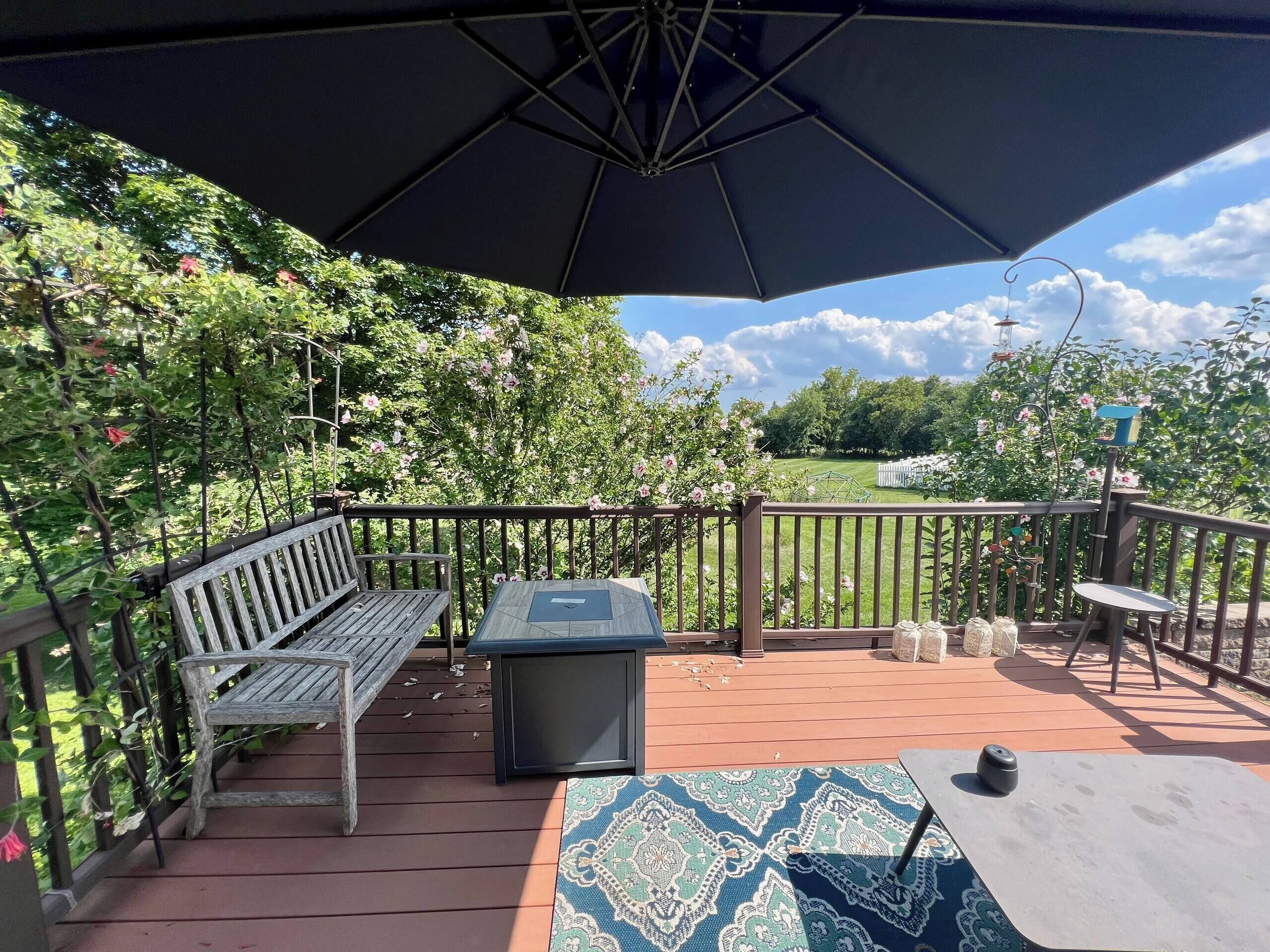 A covered outdoor deck with a bench, table, and umbrella.