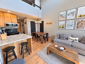 A modern kitchen with a dining area, a sofa, and a coffee table.