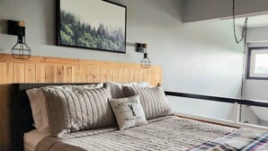 Cama com cabeceira, cobertor e travesseiros, incluindo um com texto.