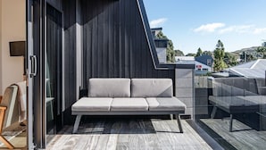 Un espace extérieur moderne aménagé avec un canapé et une porte vitrée donnant sur une pièce.