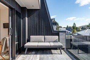 Ein moderner Außenbereich mit Sitzgelegenheiten, einer Couch und einer Glastür zu einem Zimmer.