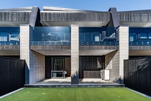 Ein modernes, zweistöckiges Gebäude mit flachem Dach, großen Fenstern und einem Balkon.