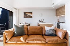 Ein modernes Wohnzimmer mit einer Ledersofa, einem Essbereich und einer Küche mit einer Holz Arbeitsplatte.