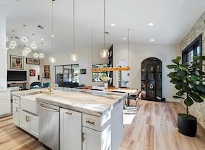 A modern kitchen with a marble island, pendant lighting, and a view to the dining area.