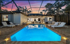Ein Schwimmbecken mit Liegestühlen und einer überdachten Terrasse.