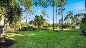 Een verzorgd gazon met bomen en een stenen muur.