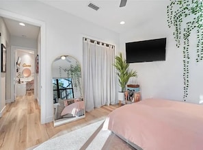Bright queen bedroom with TV, storage and natural light