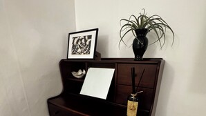 Un piano de madera oscura con un atril para partituras blancas y un cuadro encolado encima.