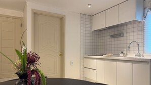 Una cocina moderna con armarios blancos, encimera negra y un florero con flores sobre la mesa.