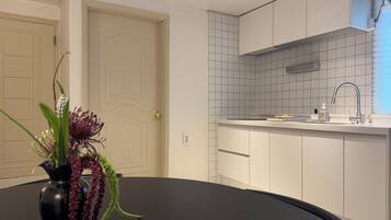 A modern kitchen with white cabinets, a black countertop, and a vase with flowers on the table.
