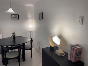 A dining area with a round table, chairs, a vase with a plant, a pendant light, a floor lamp, and books on a side table. - 군자역3분 /성수/건대/KSPO/광화문/공항버스역3분/퀸침대3개/최대6인 (Seoul)