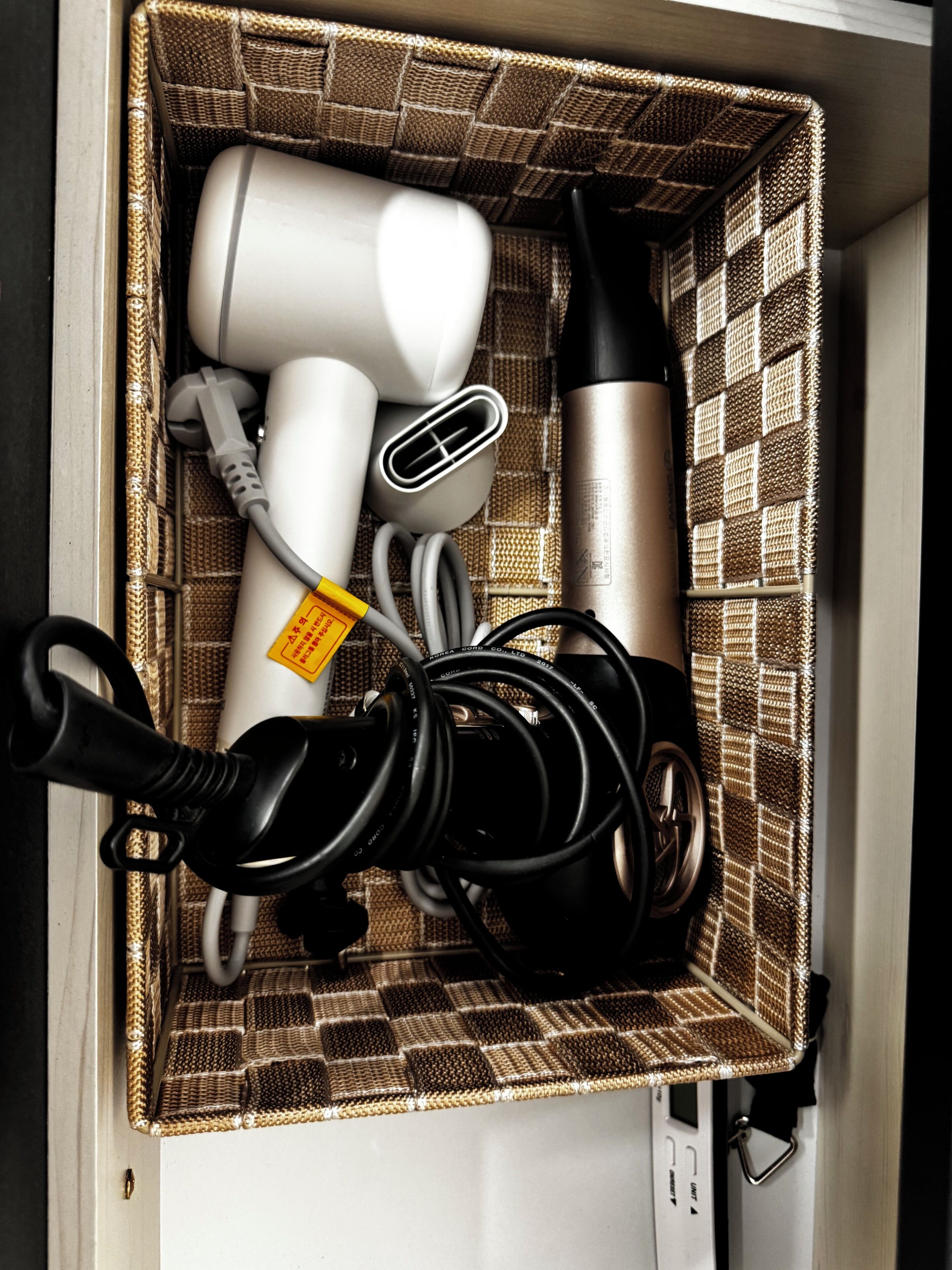 A storage box containing a hairdryer, a vacuum cleaner, and a water bottle.