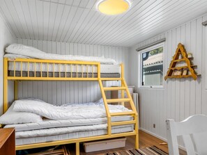 Ein Schlafraum mit Etagenbetten, einer Leiter, einem Fenster und einem Holzregal.