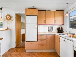 A compact kitchen with wooden cabinets, a white refrigerator, and a sink. - "Rəzvan" -  from the sea by Interhome (Hadsund)