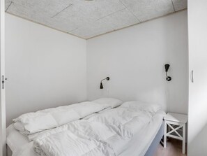 Ein helles Schlafzimmer mit einem Bett, einem Nachttisch und einer Wandlampe.
