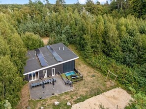 A modern building with a flat roof, solar panels, a swimming pool, and a patio area with outdoor seating. - "Carlina" -  from the sea by Interhome (Hadsund)