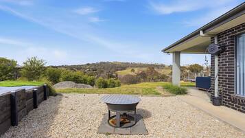 A patio area with a fire pit, gravel flooring, and a view of the countryside.