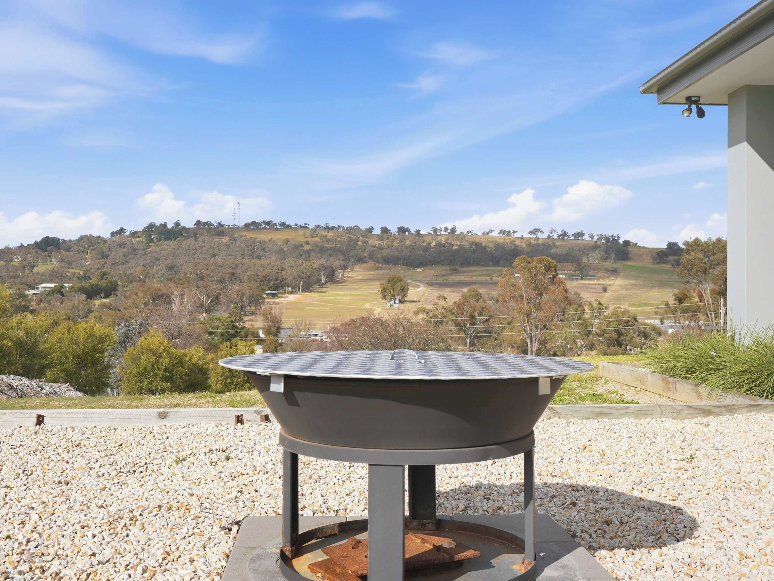 A barbecue grill with a view of a hilly landscape.